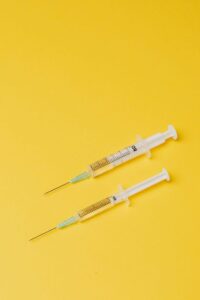 Syringes with medical drugs on yellow background
