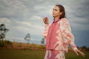 A woman in a pink and white dress is holding an apple