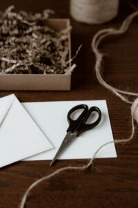 From above of blank envelope on paper with scissors and wavy thread near box with shavings on table