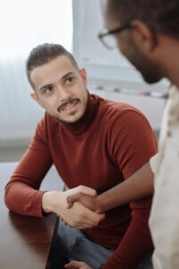 Man in Red Turtle Neck shaking Hands with a Colleague