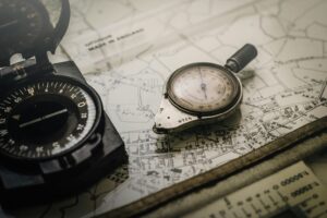 Shallow Focus Photography of Black and Silver Compasses on Top of Map