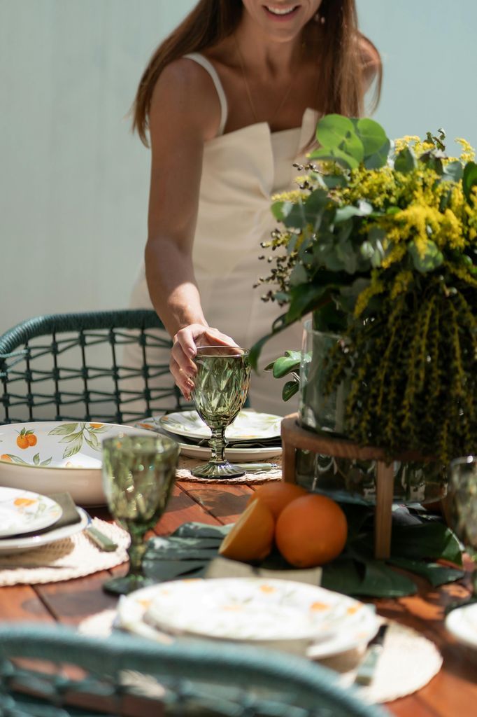 A woman setting up a table with a vase of flowers