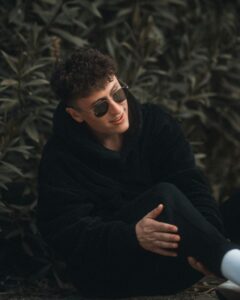 A man in sunglasses sitting on the ground