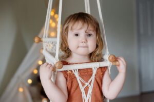 Little girl sitting on woven swing